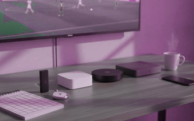 Five streaming devices, a notebook scoring grid and a stopwatch in front of a TV showing a football match