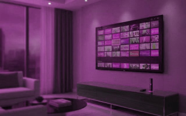 A living-room TV showing an IPTV channel guide with a streaming stick on the console